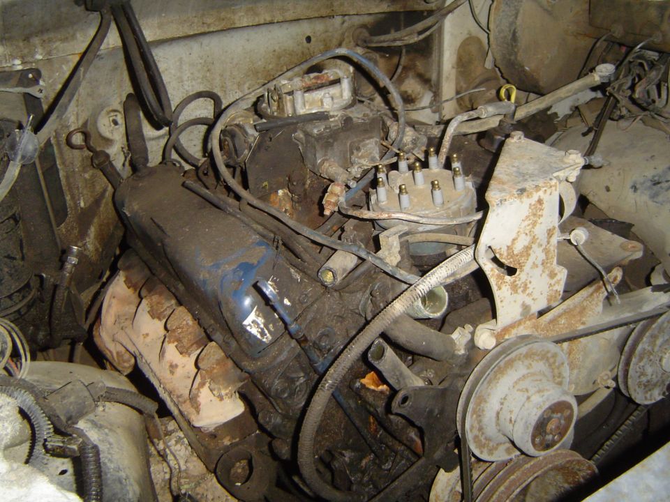 Dirty 1972 Ford F-100 engine bay with V8 engine, carburetor, and distributor visible