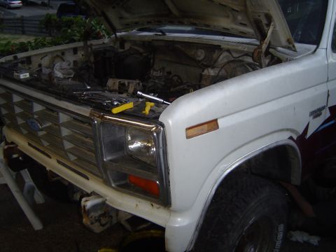 1972 Ford F-100 - The front end of a white Ford truck is shown with the hood open, revealing the engine bay and tools.