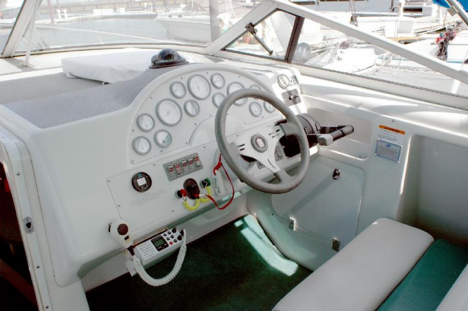 Boat dashboard with steering wheel, gauges, radio, and compass