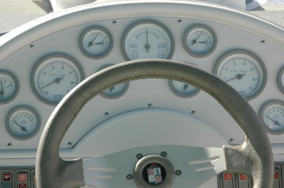 Boat dashboard with multiple gauges and a leather-wrapped steering wheel. A 'SUPERMOTORS' watermark is visible