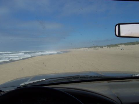 1994 Ford F-150 - Driving along the coast on a sandy beach, ocean waves visible to the left.