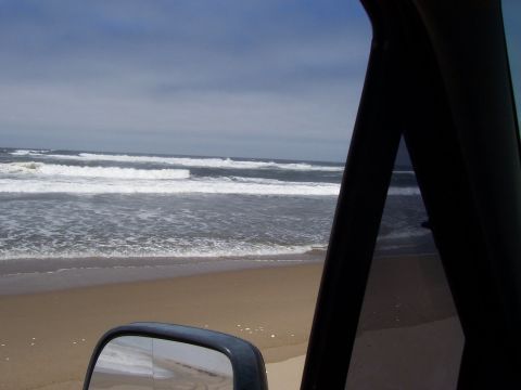 1994 Ford F-150 - View of the ocean and beach from the interior of a vehicle, including a side mirror reflecting the scene.