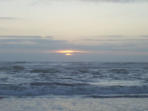 1994 Ford F-150 - The sun sets over the ocean, casting a warm glow on the clouds and waves.