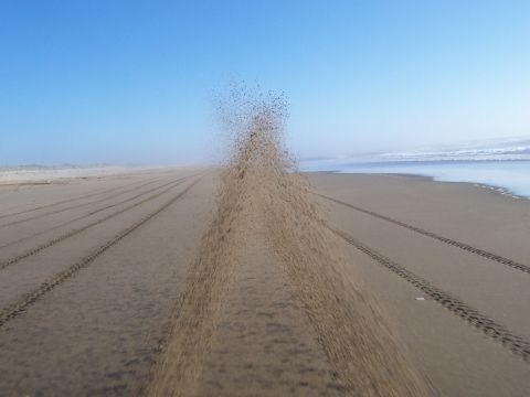 1994 Ford F-150 - Tire tracks mark a path across the sandy beach, leading towards the ocean waves.