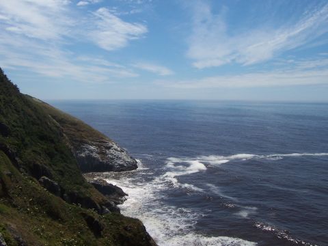 1994 Ford F-150 - A scenic view of a rocky coastline meeting the vast blue ocean under a cloudy sky.