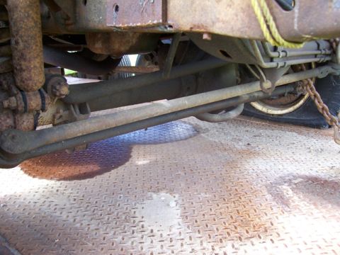 1996 Ford Bronco - Close-up of a vehicle's undercarriage, revealing suspension parts and a flat tire.