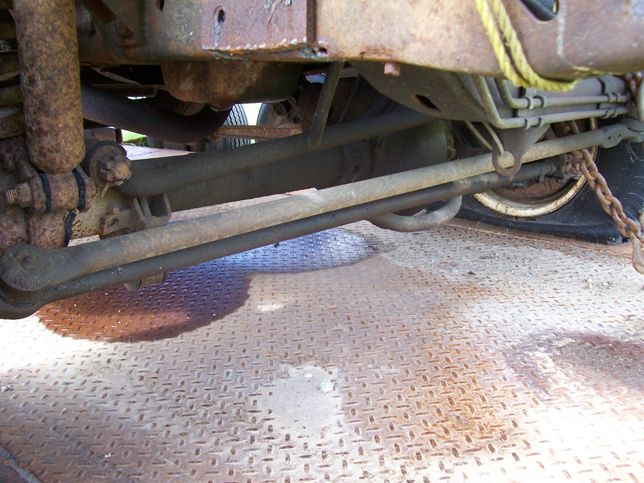 Undercarriage view showing rusty suspension components and a flat tire