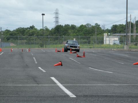 2001 Mercury Grand Marquis - A dark sedan maneuvers through an autocross course marked by orange cones in an asphalt lot.