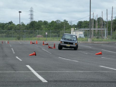 2001 Mercury Grand Marquis - A dark sedan maneuvers through an obstacle course marked by orange cones in an asphalt lot.