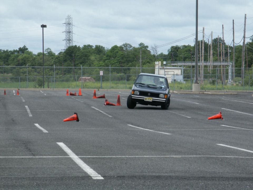 Dark sedan navigating a cone course on a cloudy day