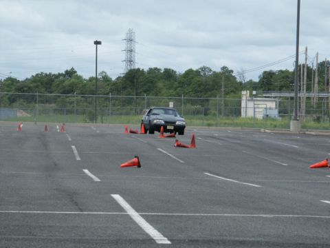 2001 Mercury Grand Marquis - Ford Mustang navigating a cone course in an empty parking lot under a cloudy sky.