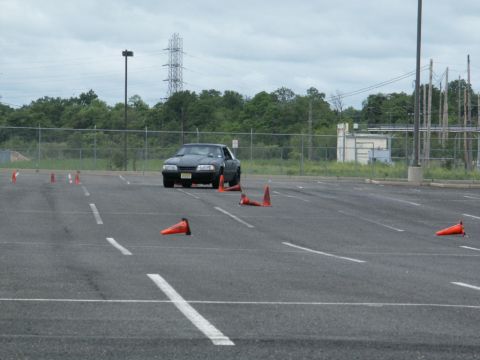 2001 Mercury Grand Marquis - A black coupe navigates a cone course in an asphalt lot under a cloudy sky.