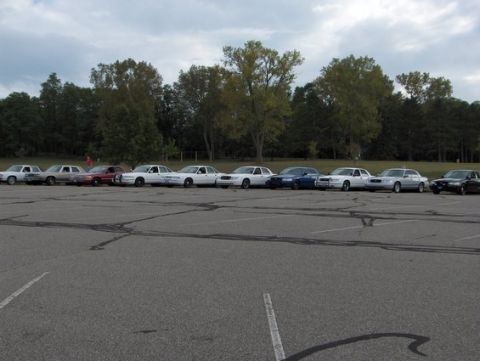 1988 Mercury Grand Marquis - Multiple sedans and a pickup truck are parked in a lot under a cloudy sky.