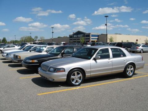 1988 Mercury Grand Marquis - A silver sedan with distinctive chrome wheels is parked in a lot in front of a Wal-Mart.