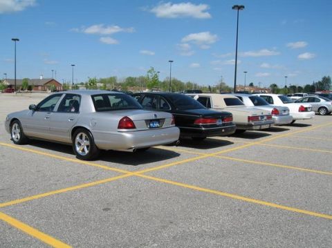 1988 Mercury Grand Marquis - Multiple sedans are parked in a lot on a sunny day.