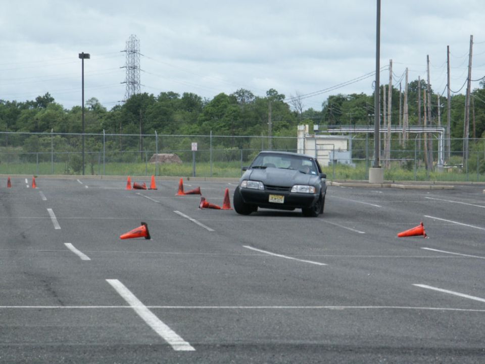 Dark coupe with a hood scoop navigates a cone course