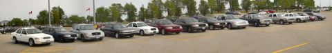 1988 Mercury Grand Marquis - A row of sedans, including a white 1988 Mercury Grand Marquis, are parked in an outdoor lot.