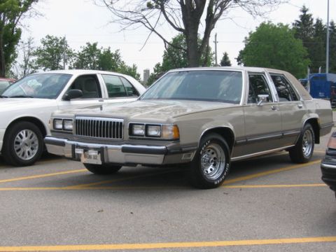 1988 Mercury Grand Marquis - A 1988 Mercury Grand Marquis is parked in a lot next to another vehicle.