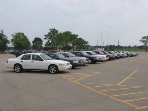 1988 Mercury Grand Marquis - A fleet of police interceptor sedans parked in a lot, with one white sedan in the foreground.