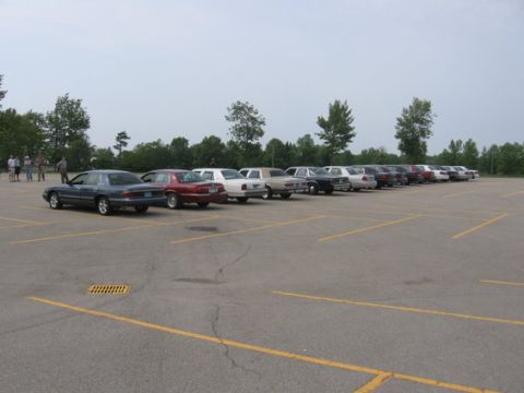 1988 Mercury Grand Marquis - A row of sedans are parked in an outdoor lot under an overcast sky.