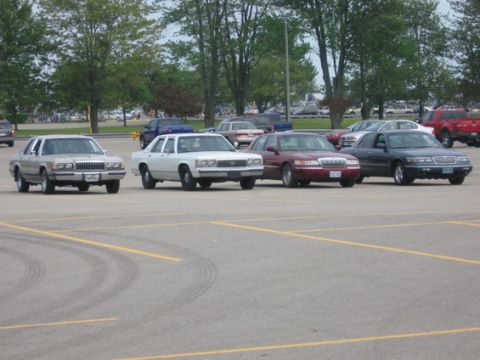 1988 Mercury Grand Marquis - Multiple sedans, including a 1988 Mercury Grand Marquis, are parked in an outdoor lot.