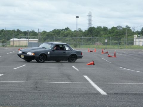 2001 Mercury Grand Marquis - A dark colored Ford Mustang navigates a course marked by orange traffic cones on an overcast day.