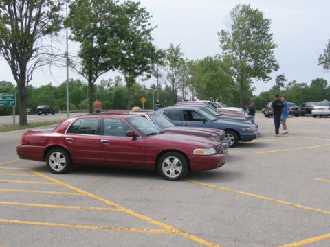 1988 Mercury Grand Marquis - A red sedan is parked in a lot with other vehicles visible in the background.