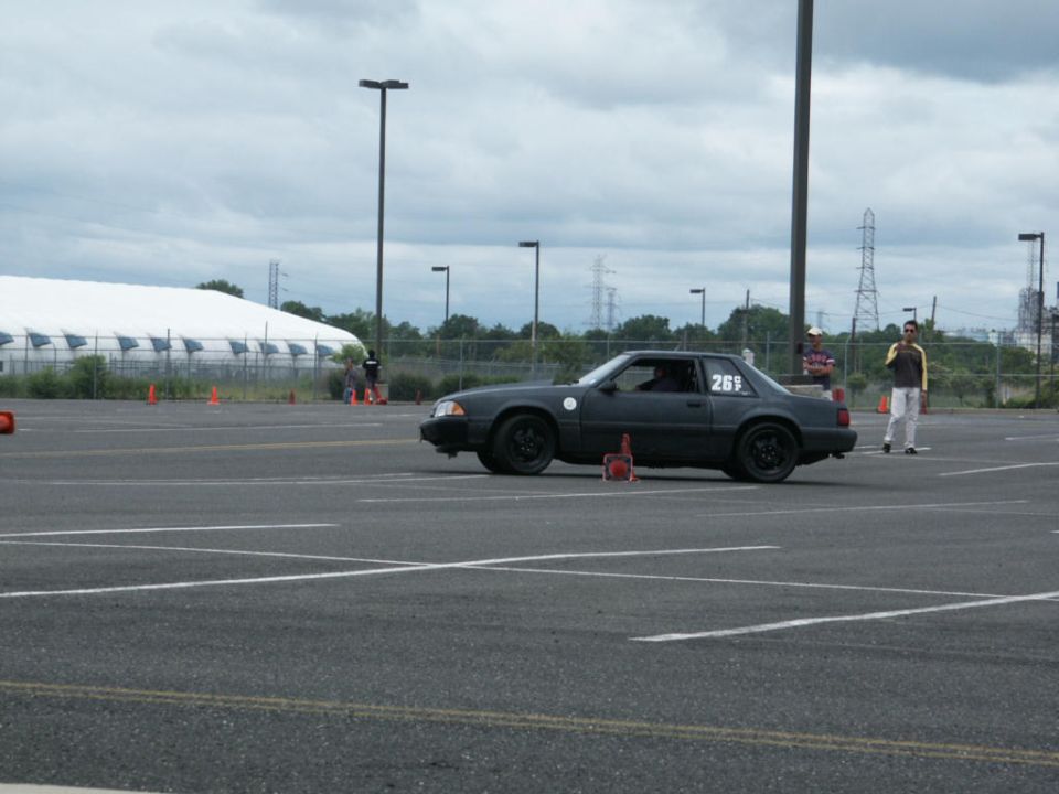 Dark gray Ford Mustang with number 269 on the door, parked on asphalt with orange cones