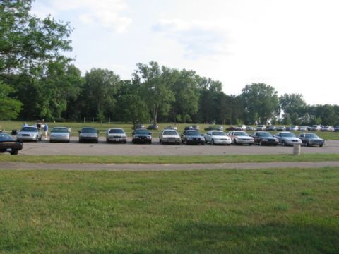 1988 Mercury Grand Marquis - Several 1988 Mercury Grand Marquis sedans are parked in a row on a paved surface with a grassy area in the foreground.