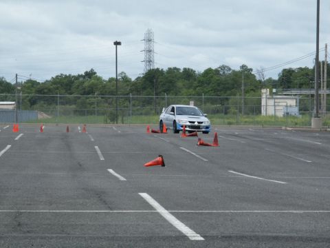 2001 Mercury Grand Marquis - A silver sedan with a prominent rear spoiler navigates a course marked by orange traffic cones on an overcast day.