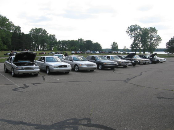 Silver Mercury Grand Marquis with hood open, parked in a lot with other cars