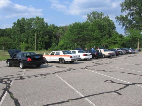 1988 Mercury Grand Marquis - A row of sedans are parked in an outdoor lot under a partly cloudy sky.
