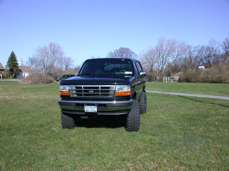 Front view of a black lifted Ford Bronco with chrome grille on a grassy lawn