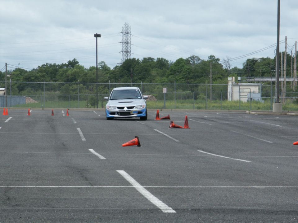 Silver Mitsubishi Lancer Evolution VIII with blue accents driving through cones in a parking lot