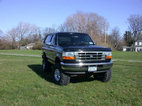 1996 Ford Bronco - This 1996 Ford Bronco is shown in a 3q-front view, parked on a grassy field under a clear blue sky.