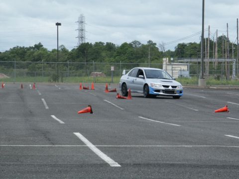 2001 Mercury Grand Marquis - A silver sedan with a blue front bumper and a rear spoiler drives through a cone course on an overcast day.