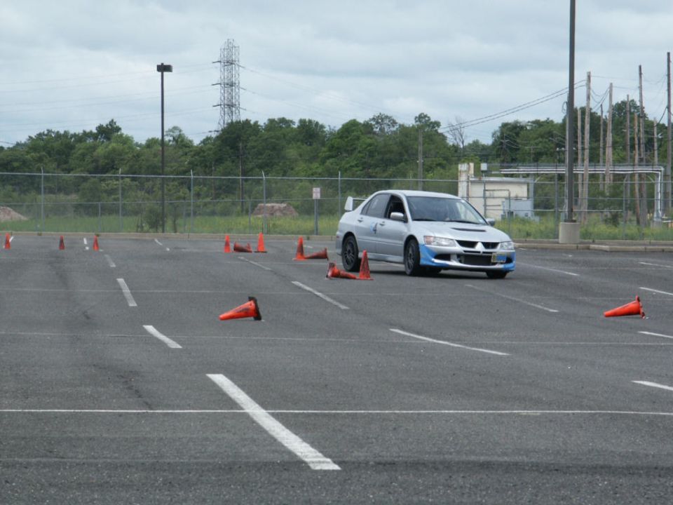 Silver sedan with a blue front bumper and a rear spoiler navigates a cone course