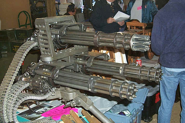 Minigun with ammo belt, people in background