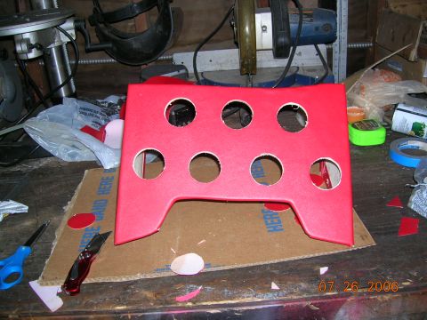 1985 Ford Bronco - A red gauge pod sits on a workbench, surrounded by tools and materials for installation.