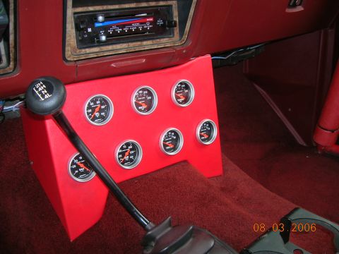 1985 Ford Bronco - Aftermarket gauges are installed in a custom red panel in the center console of a vehicle.