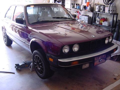 1984 BMW 3 Series - A purple 1984 BMW 3 Series coupe is elevated on jack stands inside a garage.
