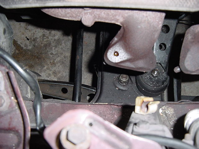 Close-up of a vehicle's engine mount with visible rust and a water droplet
