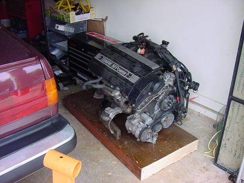 1984 BMW 3 Series - A BMW M Power engine is displayed on a wooden pallet in a garage setting.