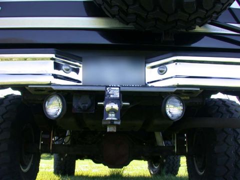 1996 Ford Bronco - The rear bumper and hitch assembly of a truck are visible, round auxiliary lights and a spare tire mounted above.