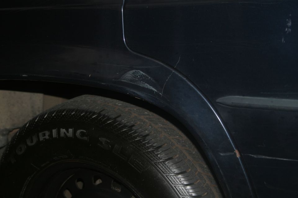 Dark blue quarter panel with scratches above a Touring SL tire on steel wheel
