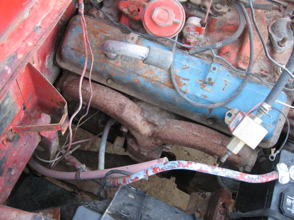 Close-up of a rusty engine bay with blue valve covers and red block