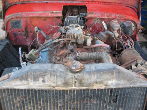 1983 Chevrolet Silverado 1500 - The engine bay of a red vehicle is shown, a carburetor and radiator, with visible text from Supermotors.net.