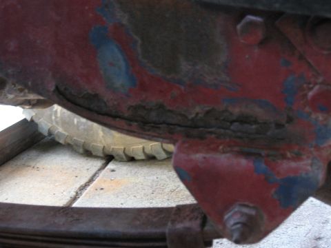 1983 Chevrolet Silverado 1500 - A close-up view of a weathered, painted metal component, possibly from a vehicle's undercarriage, with a tire in the background.