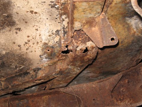 1983 Chevrolet Silverado 1500 - Frame rail shows significant rust damage and holes, with a metal bracket attached.