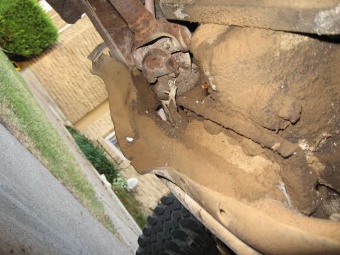 1983 Chevrolet Silverado 1500 - The underside of a vehicle shows drivetrain components and a tire tread, with a watermark for SuperMotors.net.